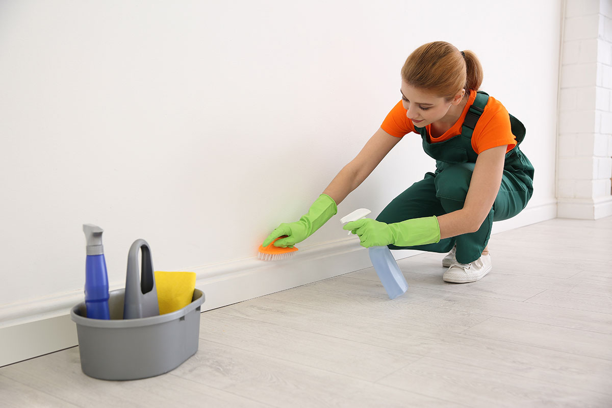 Woman deep cleans baseboards